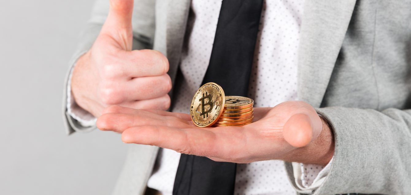 Close up of man holding stack of golden bitcoins