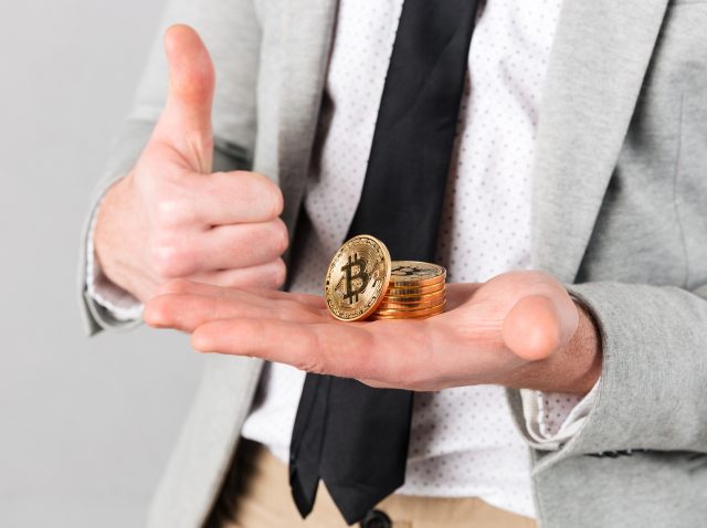 Close up of man holding stack of golden bitcoins