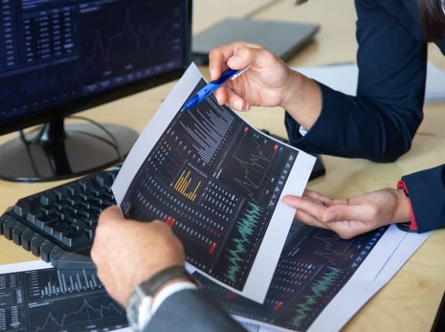 imgi_4_brokers-discussing-trading-strategy-holding-papers-with-financial-data-pointing-pen-charts-cropped-shot-broker-job-stock-market-exchange-concep